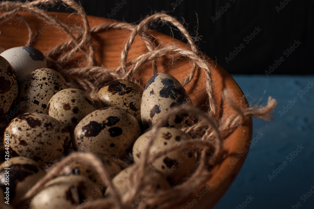 quail eggs in wooden bowl isolated on blue background close up quail eggs in wooden bowl isolated on blue background close up