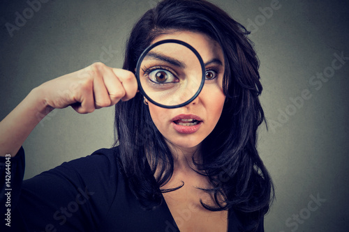 Surprised woman looking through magnifying glass