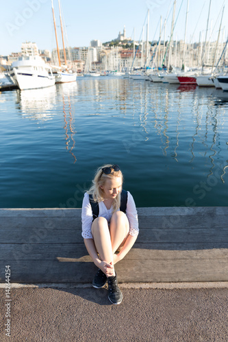 Pretty woman sitting alone at the seashore. Marina in the background © Myvisuals