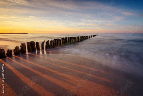 Beautiful sunset over Baltic sea with wooden breakwaters. Poland
