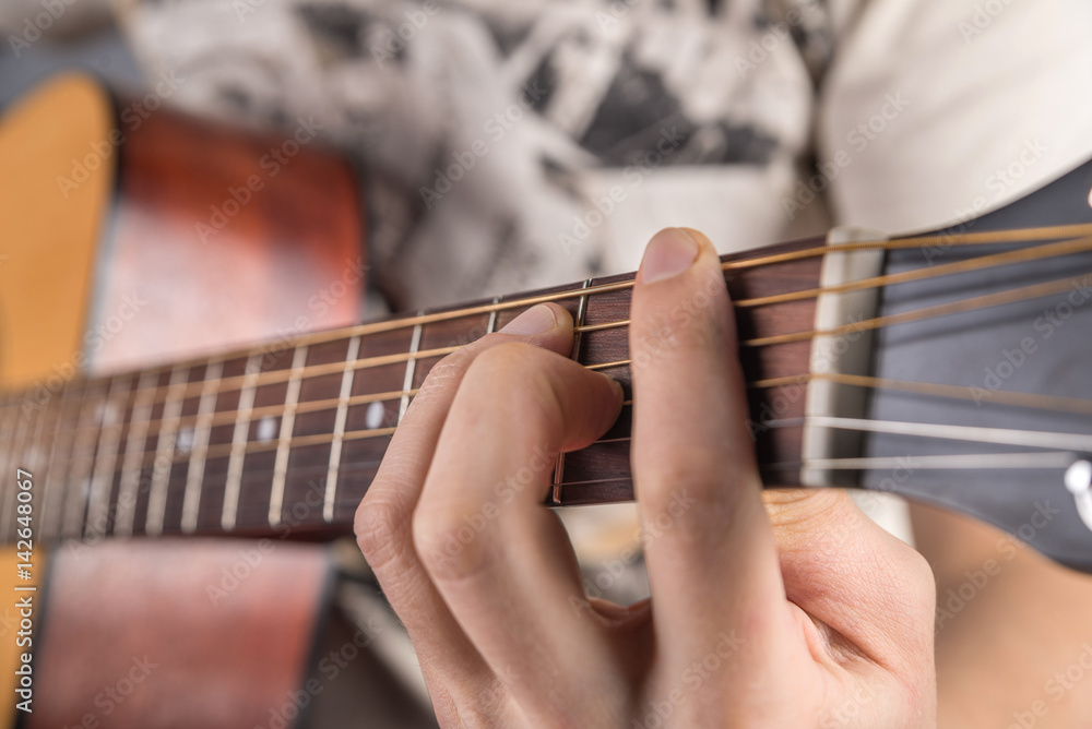 Fototapeta premium A picture of an acoustic guitar, classical color, in the hands of a guitarist