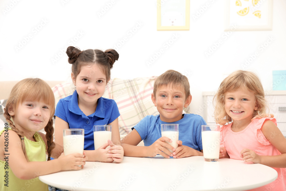 Happy children with glasses of milk at table Happy children with glasses of milk at table