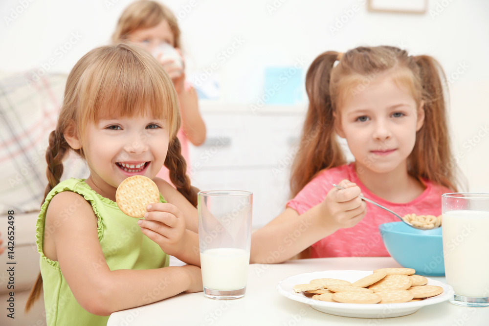Children at table eating cookies, cornflakes and drinking milk Children at table eating cookies, cornflakes and drinking milk