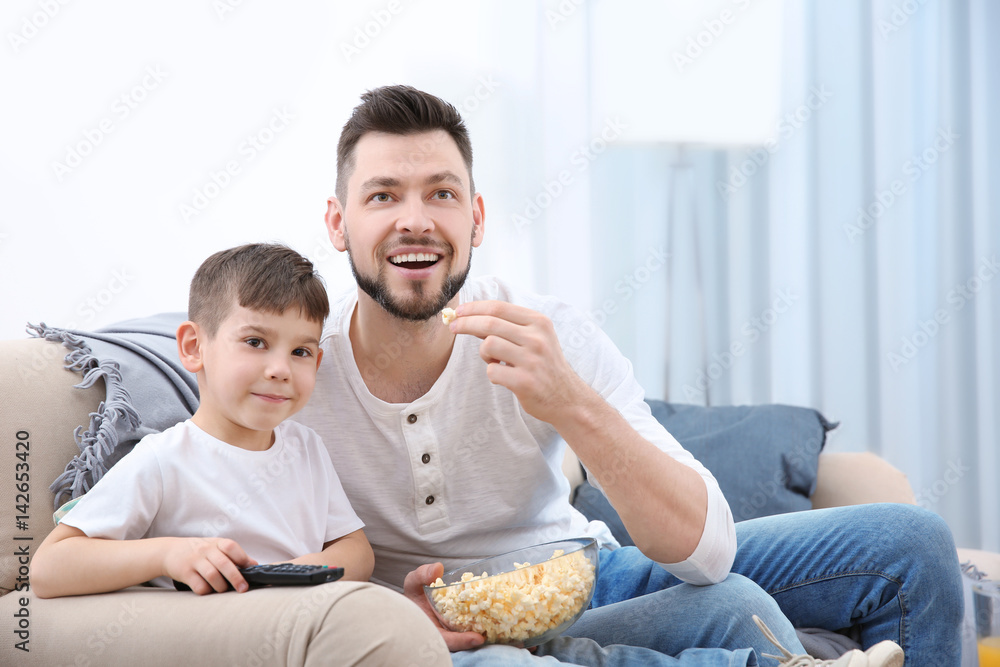 Father and son watching TV at home Father and son watching TV at home