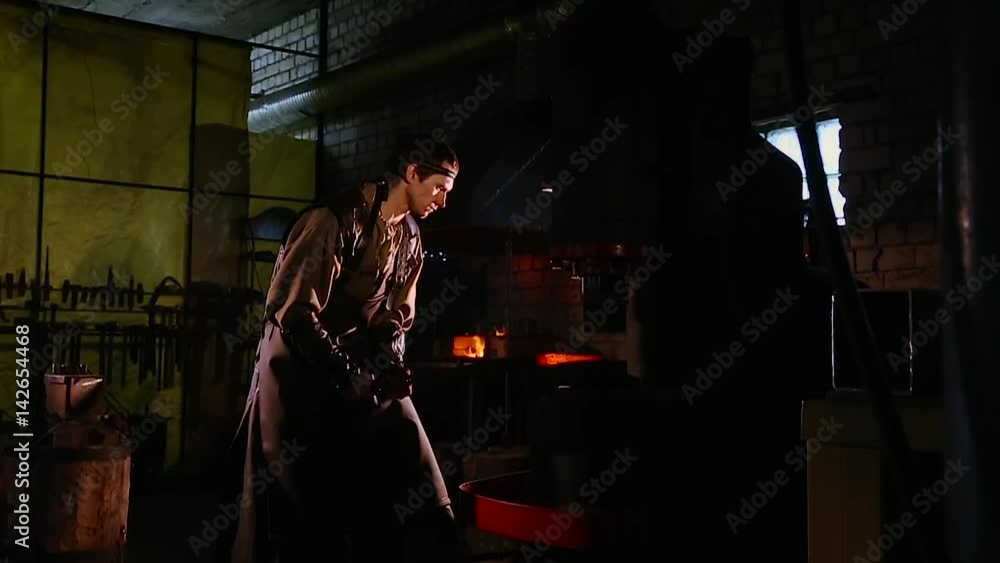 Worker operates with automated Metalworking machine at a metal forging factory. Worker operates with automated Metalworking machine at a metal forging factory.