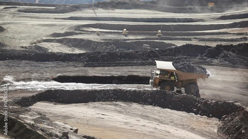 Heavy equipment digs and hauls ore inside an enormus open pit mine. photo