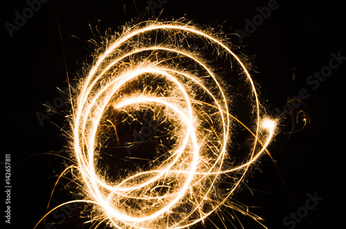 A glowing red hot sparkler light trail isolated in dark environment using slow shutter speed.