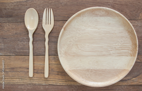 Top view shot of handmade wooden spoon and fork beside plate.
