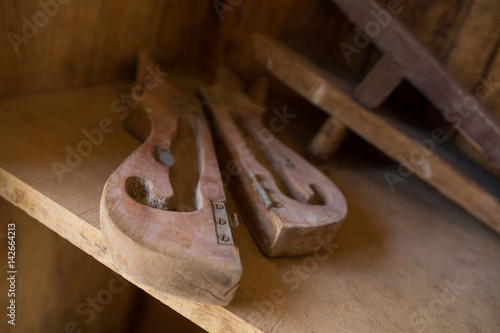 A dusty broken pair of antique wooden bellows in an all brown wooden setting. photo