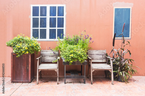 Wooden chair with flower against orange concrete background. © Pheniti