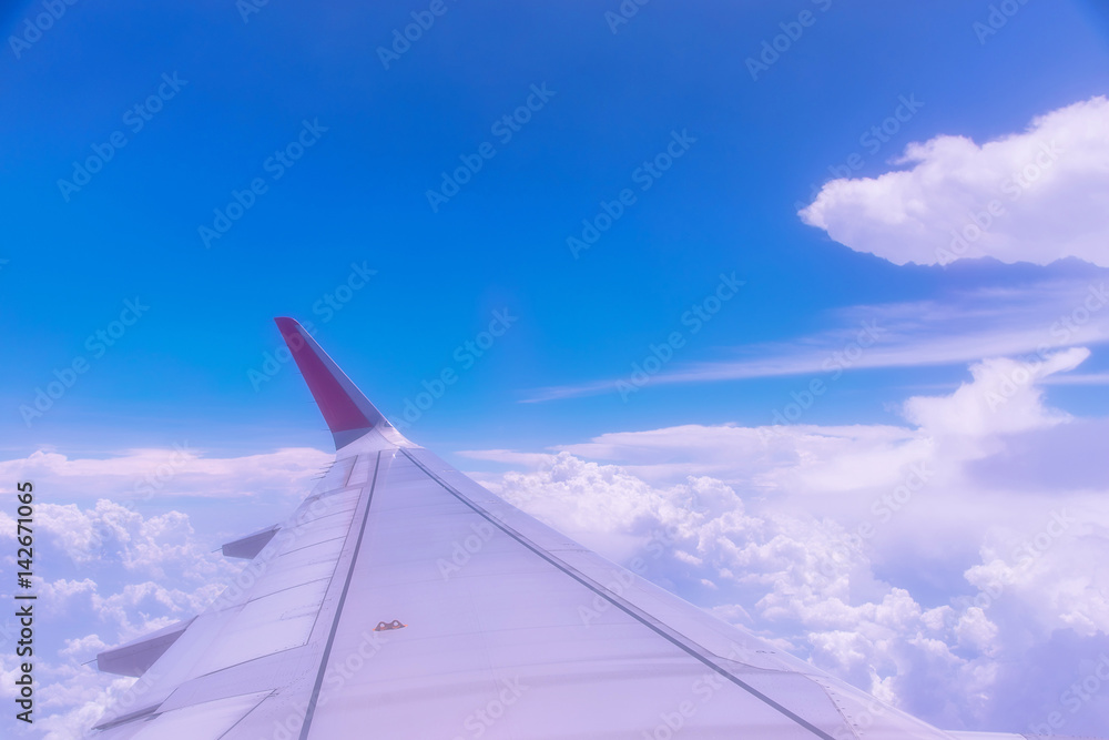 Wing of an airplane above white clouds.