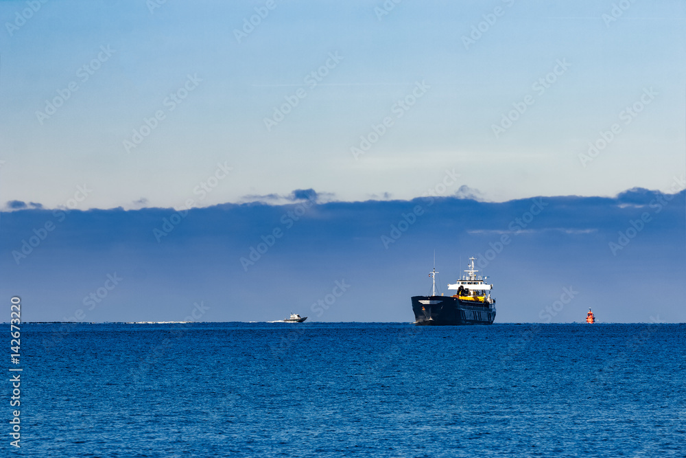 Fototapeta premium Black cargo ship with long reach excavator moving by baltic sea