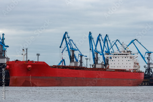 Red cargo ship loading in the port of Riga, Europe