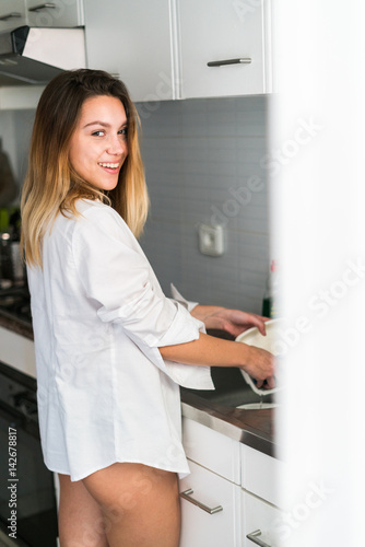 Cheerful woman washing dishes photo