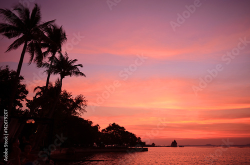 Tropical beach with palm trees at sunset