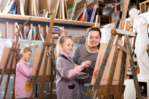 Female teacher helping girl during painting class