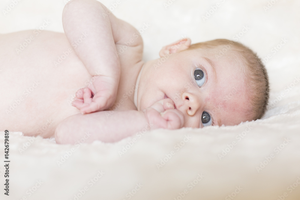 Portrait of a cute baby girl awake, looking at the camera. White blanket background Portrait of a cute baby girl awake, looking at the camera. White blanket background