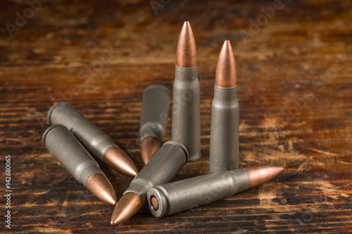 Rifle cartridges caliber 7.62 x 39 mm on wooden background. 