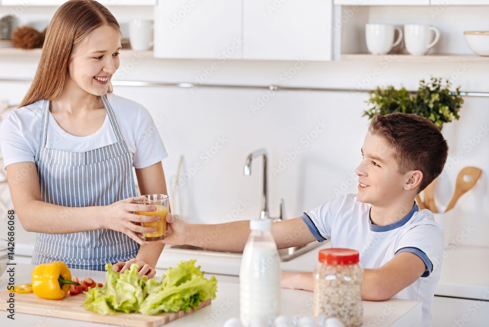 Positive young siblings standing in the kitchen Positive young siblings standing in the kitchen