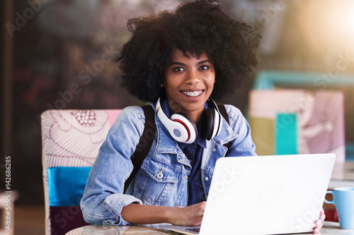 Beautiful young african american student girl with a lot of books and laptop