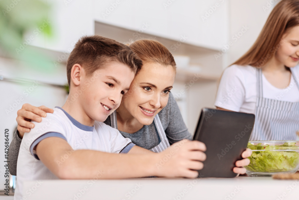 Positive mother using tablet with her son in the kitchen Positive mother using tablet with her son in the kitchen
