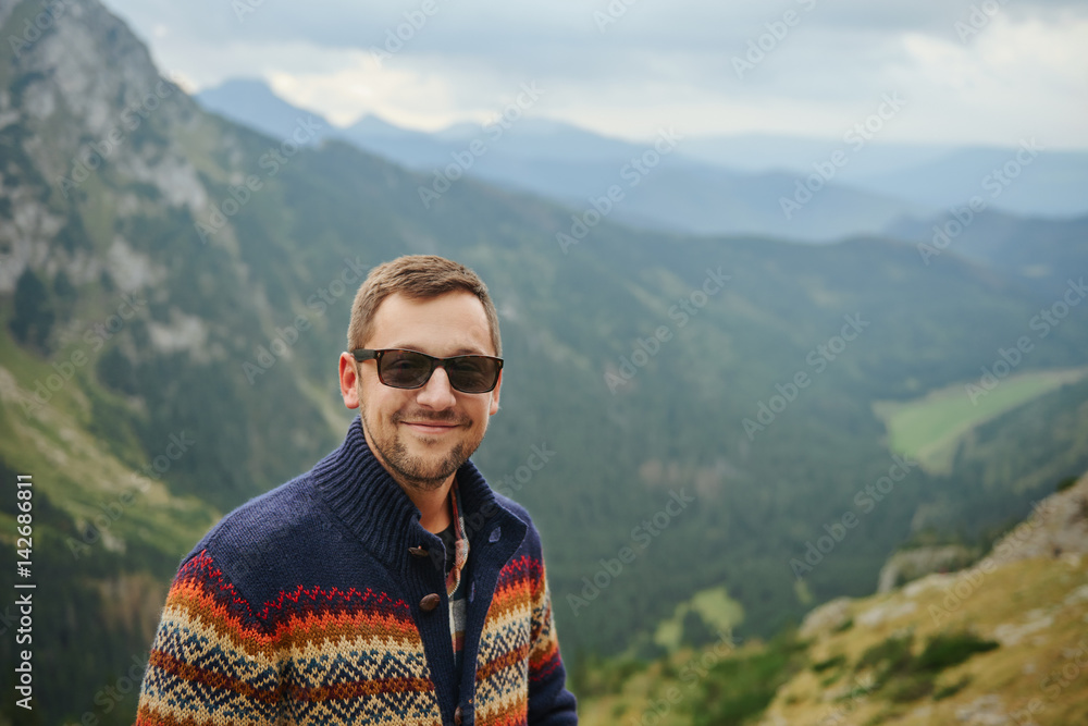 Smiling hiker standing in front of a majestic mountain landscape