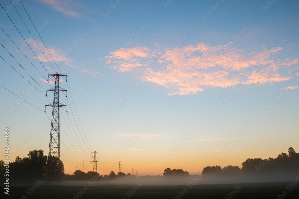 Field with power towers during early morning