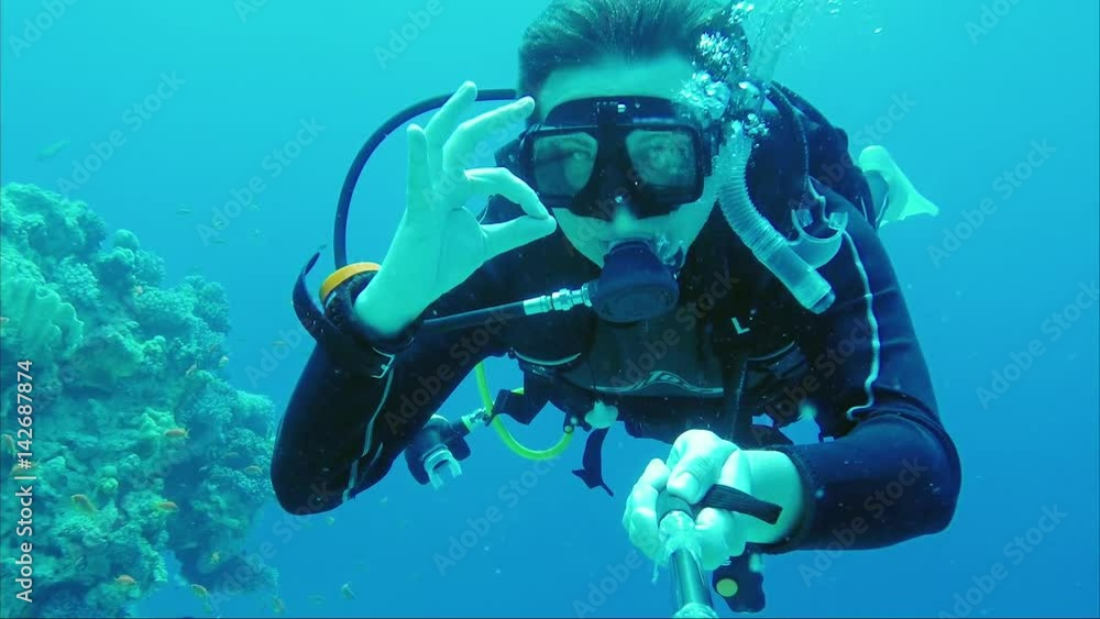 Excellent vacation and diving in the warm sea. The scuba diver signs the okay sign and takes himself off on a video of Self pin