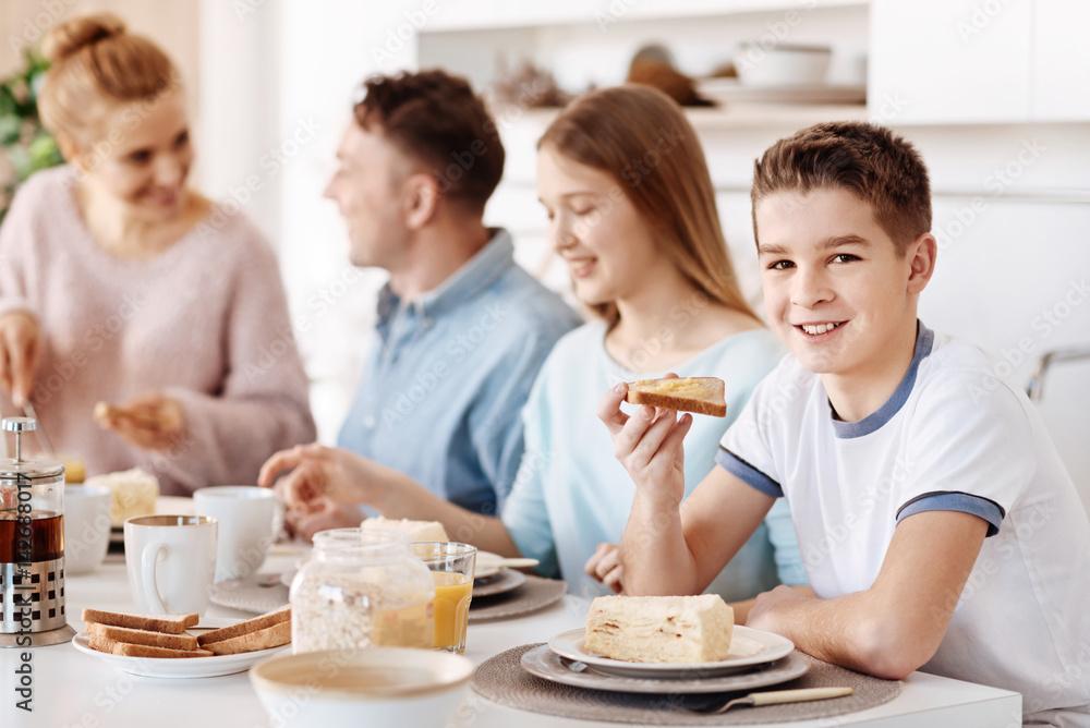 Pleasant smiling boy having breakfast with his family Pleasant smiling boy having breakfast with his family