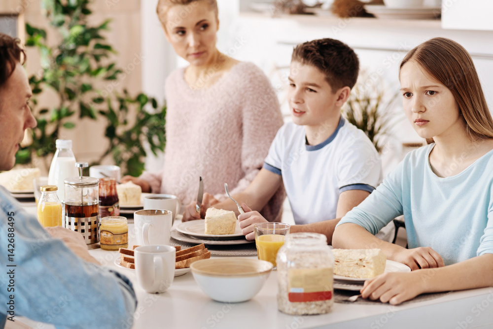 Confused girl having breakfast with her family
