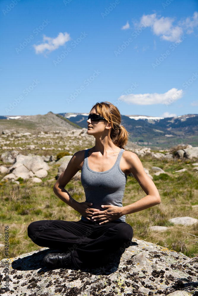 femme assise dans les montagnes qui fait du yoga