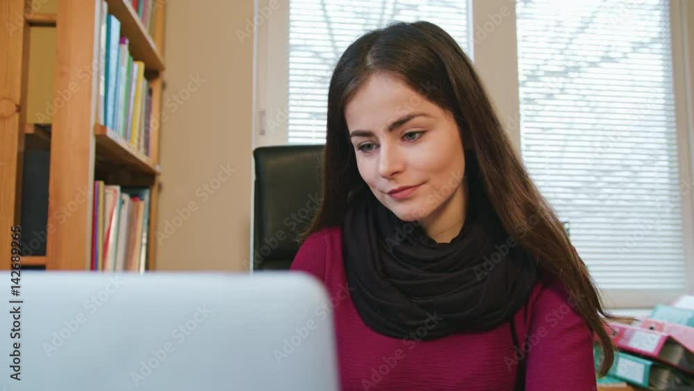 Brunette woman freelance working at home on laptop computer, typing and smile, dolly shoot Brunette woman freelance working at home on laptop computer, typing and smile, dolly shoot