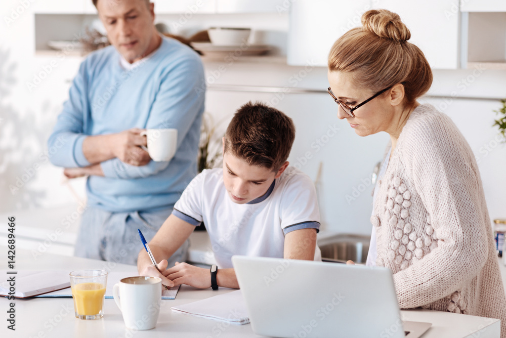 Diligent boy doing homework with his parents Diligent boy doing homework with his parents