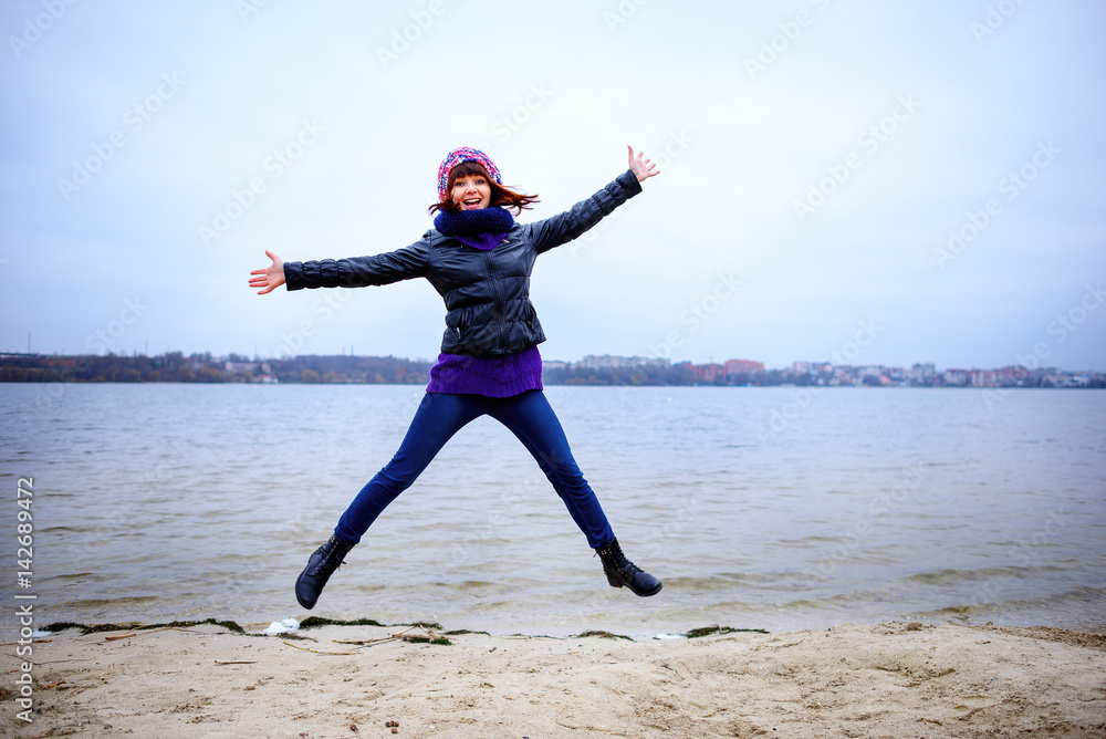 Happy young woman jumping on the beach in autumn Happy young woman jumping on the beach in autumn