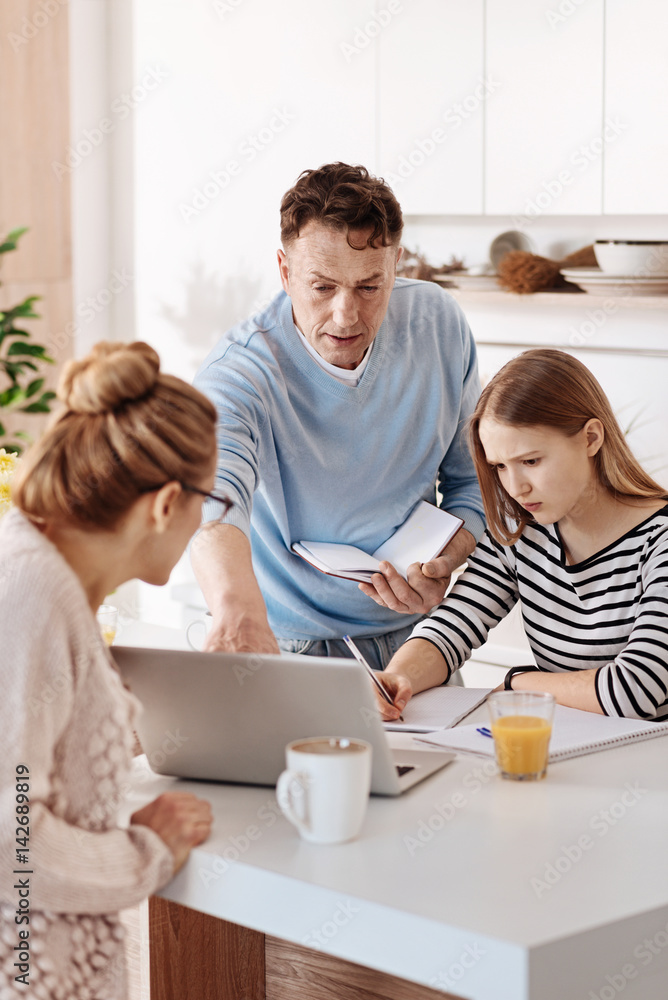 Pleasant girl doing homework with her parents Pleasant girl doing homework with her parents