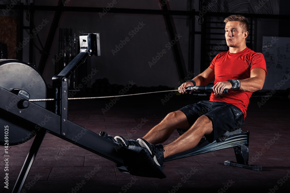 young man using rowing machine in the gym