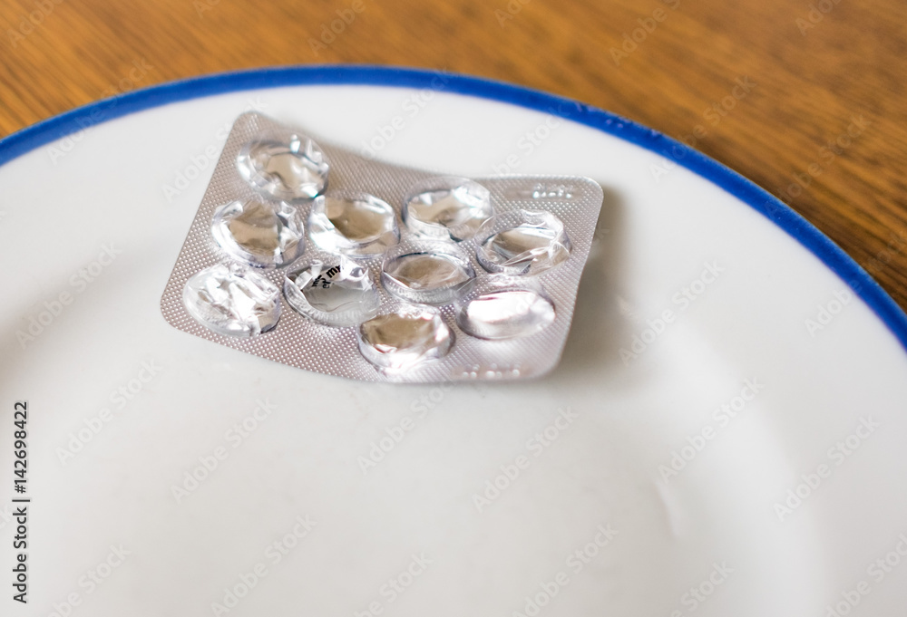 Set of pills in a plastic and foil package lying on white tray with blue rim Set of pills in a plastic and foil package lying on white tray with blue rim