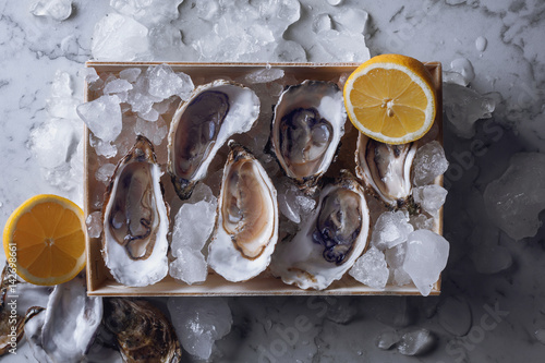 Oyster box with ice and lemon over a gray marble table
