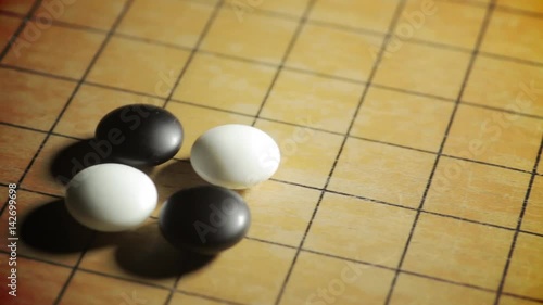 Horizontal dolly shot of a Go board game, with black and white stones, and a hand placing a piece.