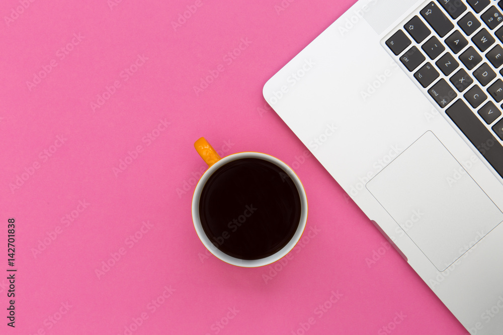 Coffee cup and laptop computer overhead on bright pink background Coffee cup and laptop computer overhead on bright pink background