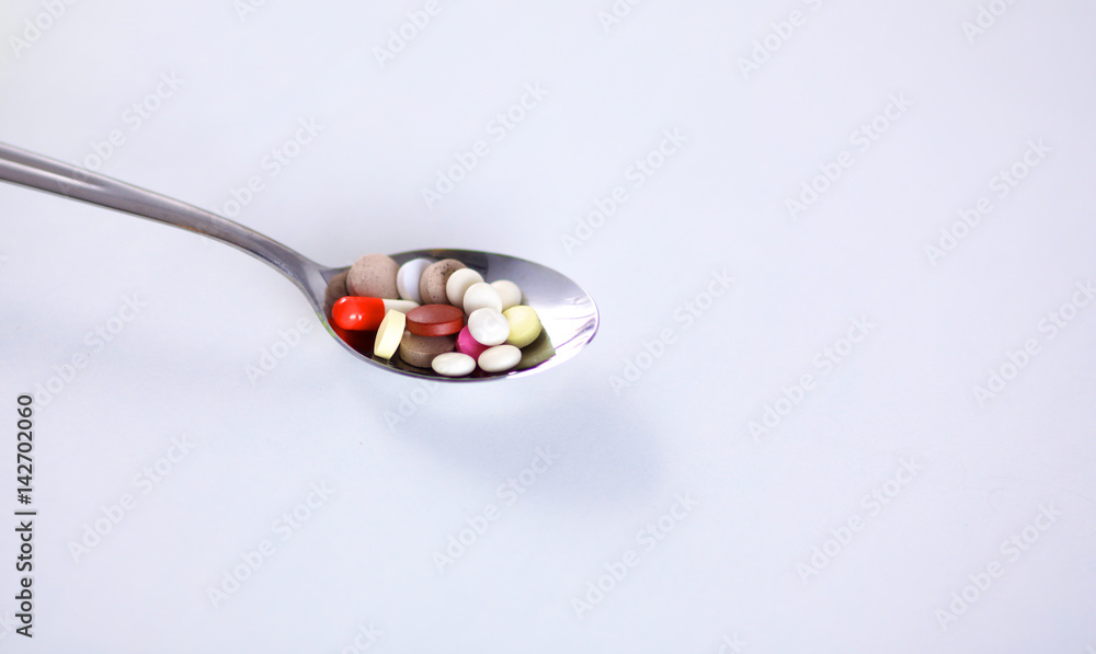 Pills and sugar in a spoon isolated against white Pills and sugar in a spoon isolated against white