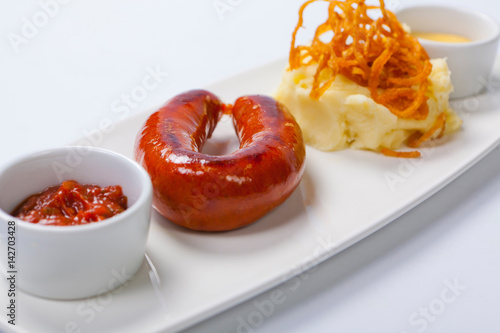 Sausage with potatoes and sauerkraut on a white plate photo