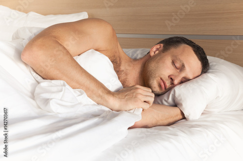 Portrait European man sleeping in white bed