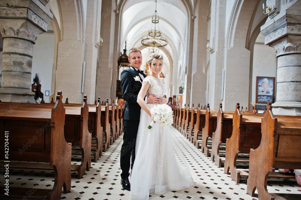Photosession of stylish wedding couple on catholic church.