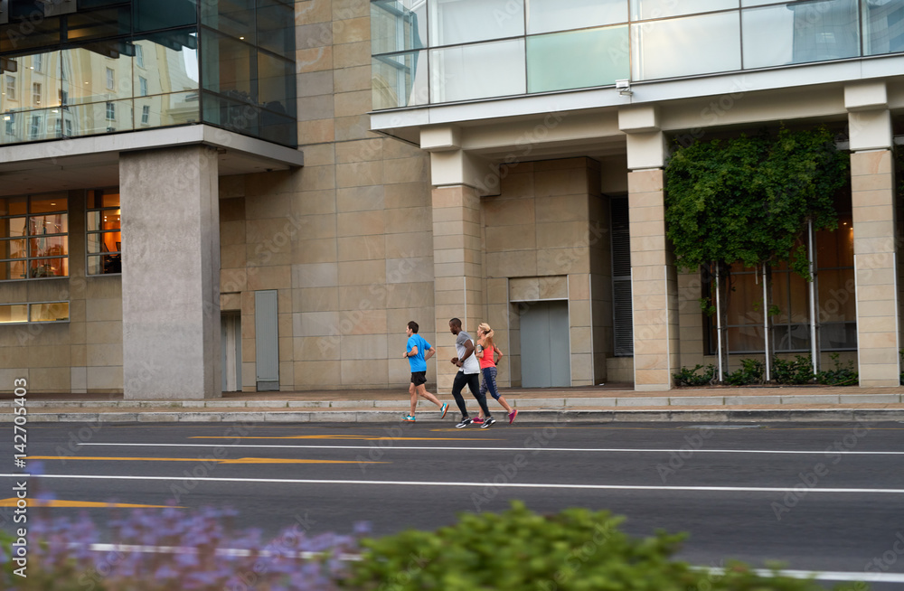 Athletic people running in city, past modern building Athletic people running in city, past modern building