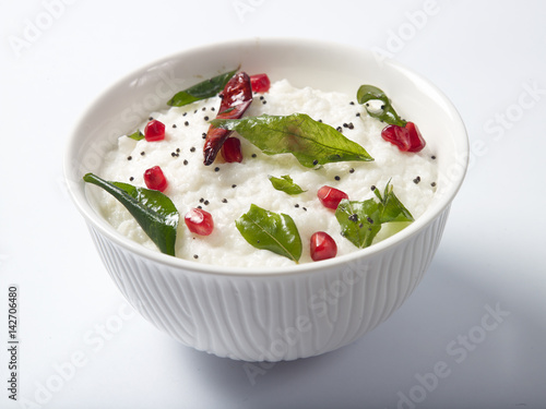 Curd rice served in a white bowl on white background