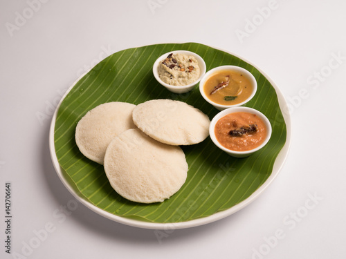 idli with sambar coconut chutney and kara chutney served in a banana leaf