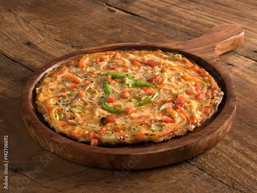 Mixed vegetables pizza served in a wooden plate on wooden background