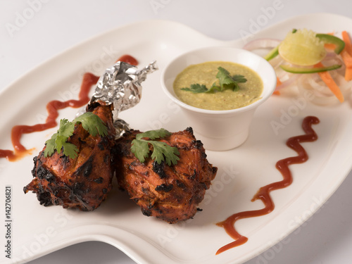 Tangdi kabab with mint-yogurt chutney served in a white plate  photo