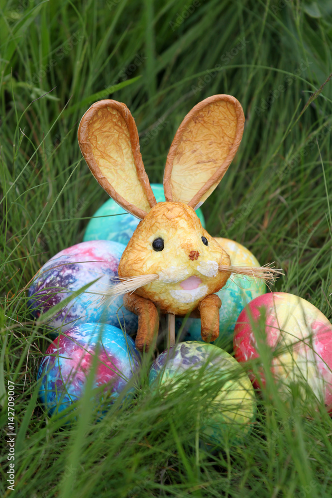 Fototapeta premium Colored Easter eggs and rabbit on green grass background